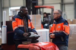 deux hommes discutent dans un entrepôt