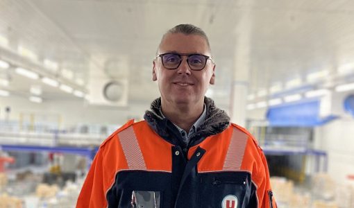 Thierry Guillet, nouveau Directeur du site logistique U LOG de Savigny-en-Véron, en tenue de travail de la logistique avec le logo U, souriant, dans un entrepôt U LOG.