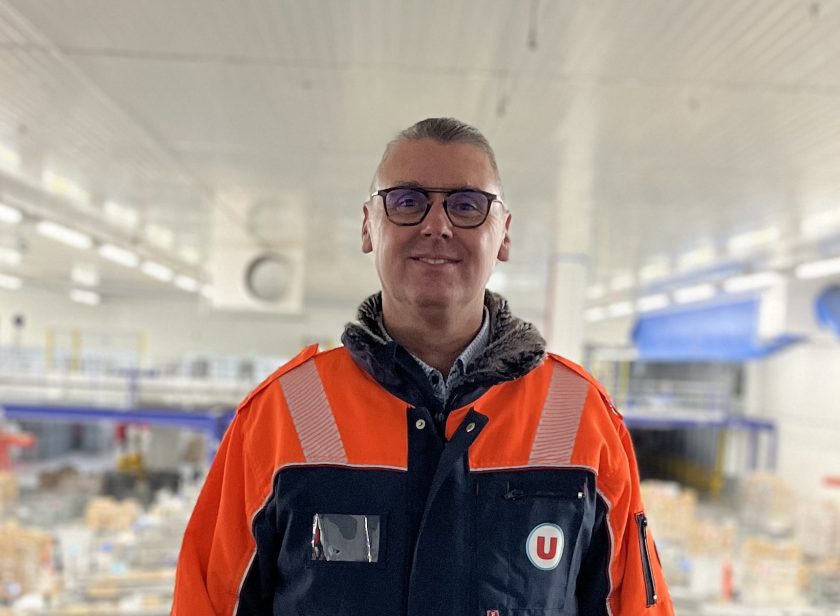 Thierry Guillet, nouveau Directeur du site logistique U LOG de Savigny-en-Véron, en tenue de travail de la logistique avec le logo U, souriant, dans un entrepôt U LOG.